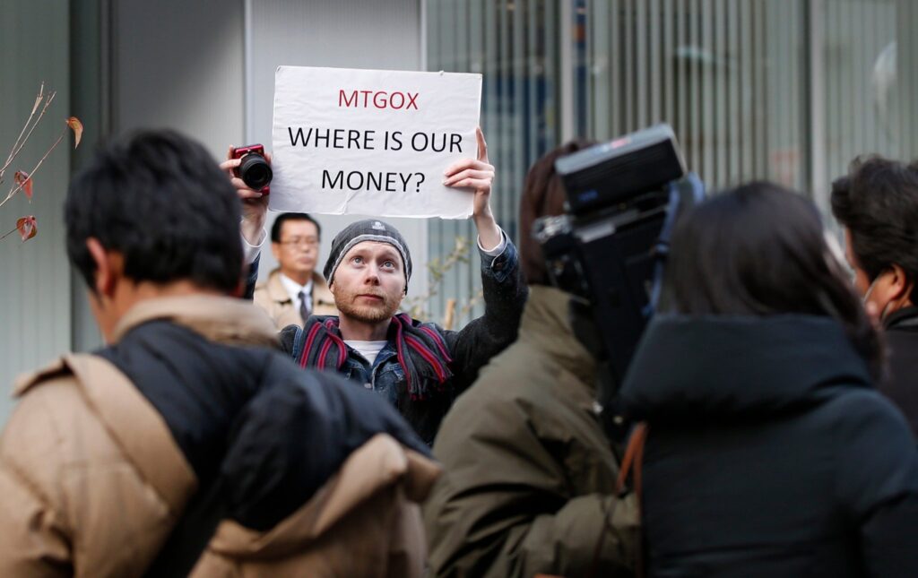Homem com um cartaz dizendo "Mt. Gox onde está o nosso dinheiro?"